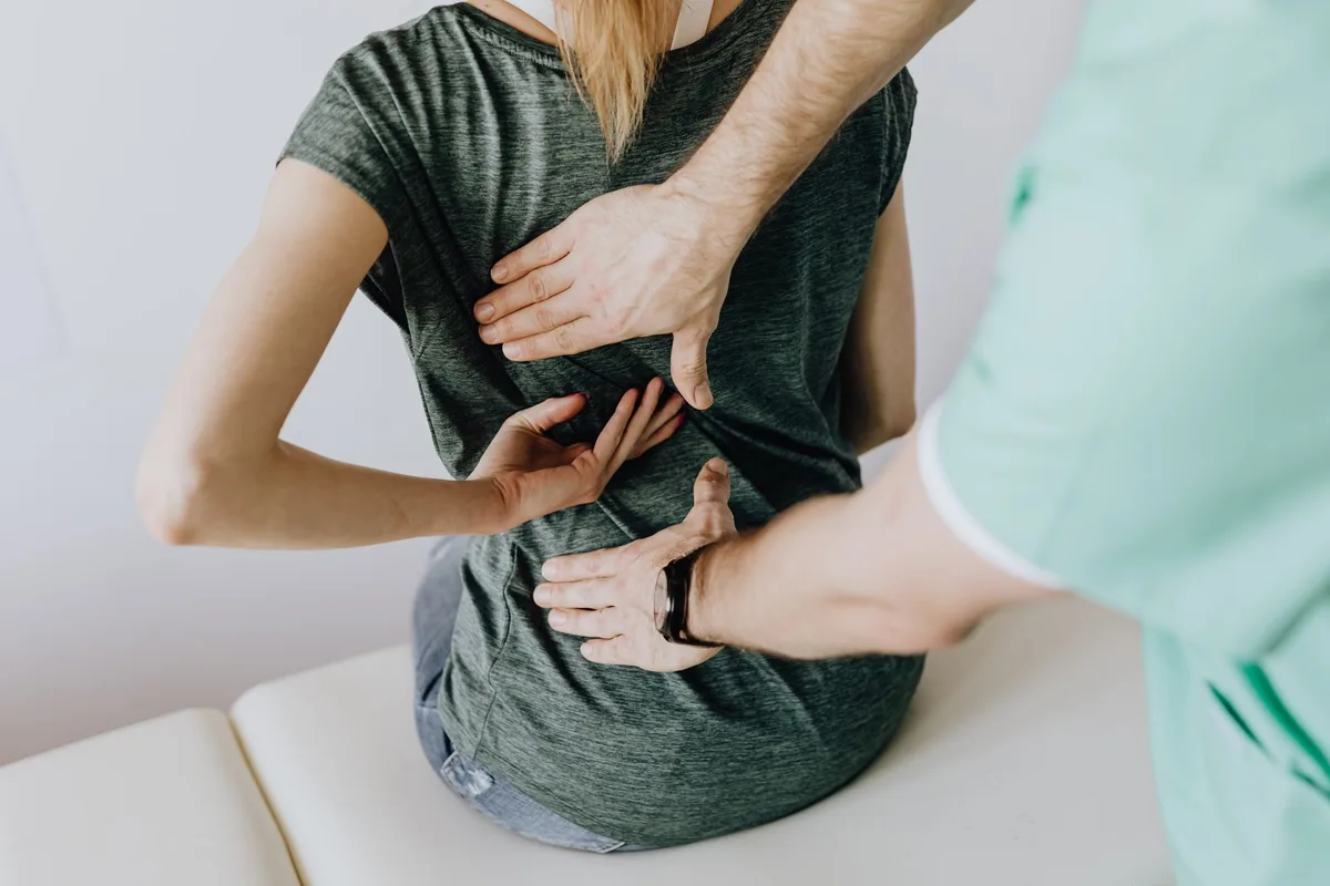 A clinician testing arm strength and reflexes as part of a cervical radiculopathy exam.