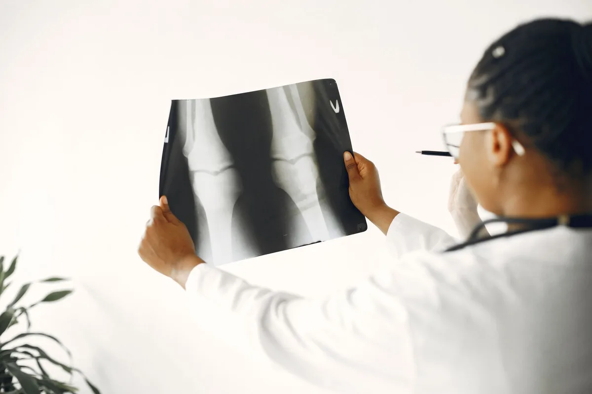 A fluoroscopic imaging setup positioned over a knee during a genicular nerve procedure.