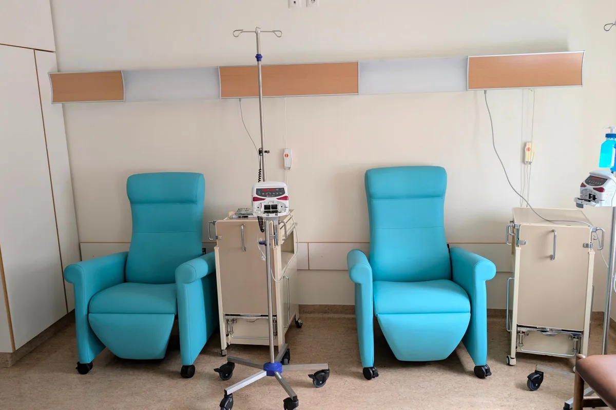 A patient receiving a monitored IV infusion in a clinical treatment chair.