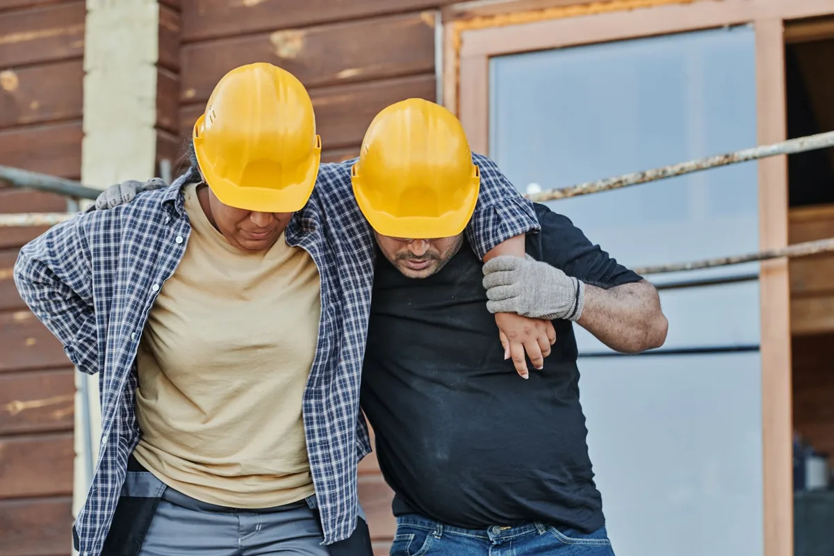 A tradesperson pausing mid-lift, hand on lower back.