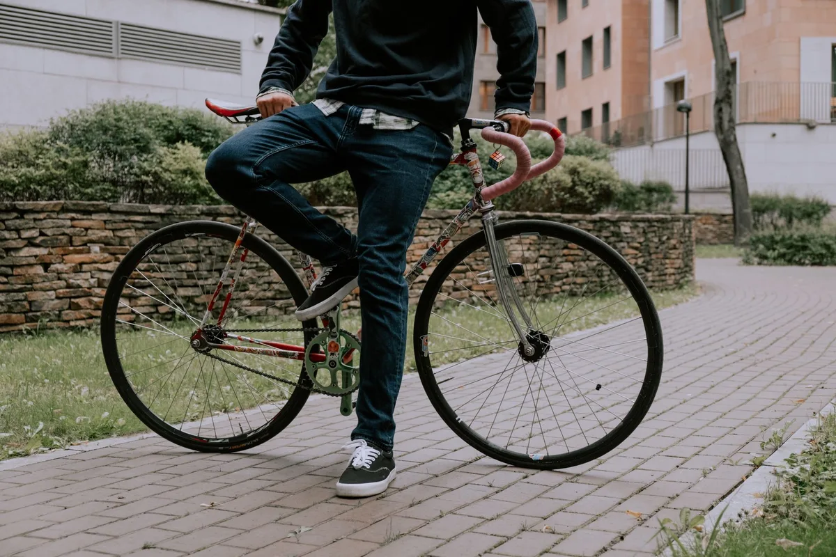 A young cyclist examining a sore knee on a city street.