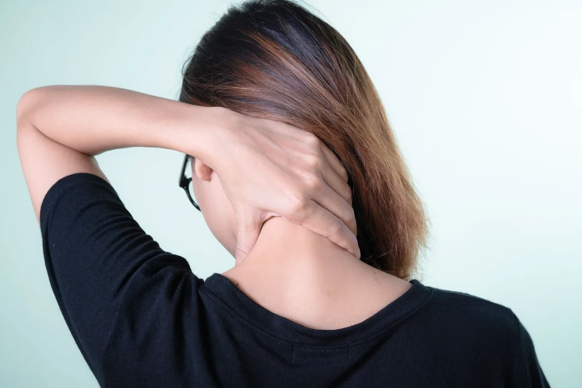 A clinician palpating a patient's upper back to locate a muscle trigger point.