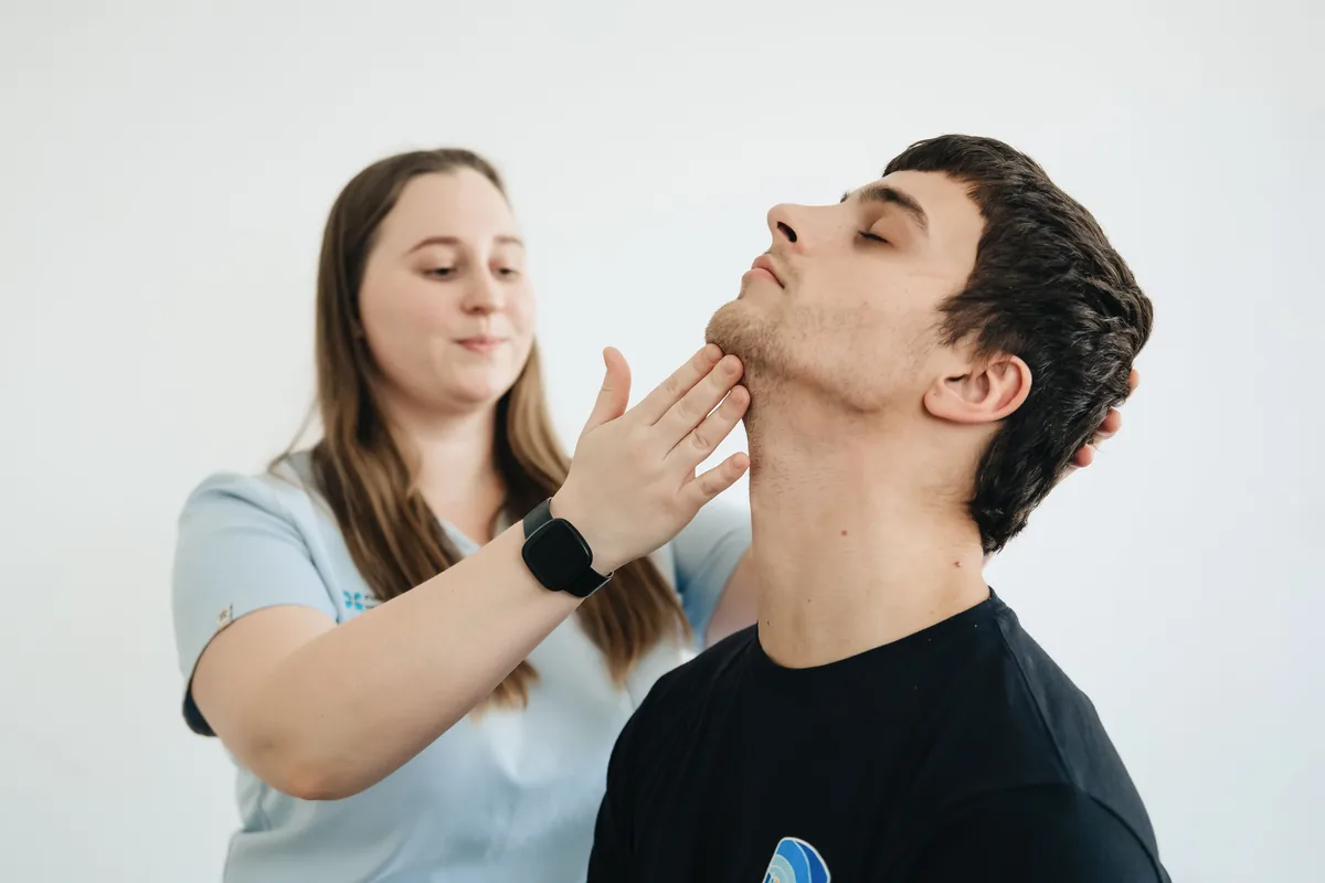 A clinician turning a man's head to one side while examining his neck.