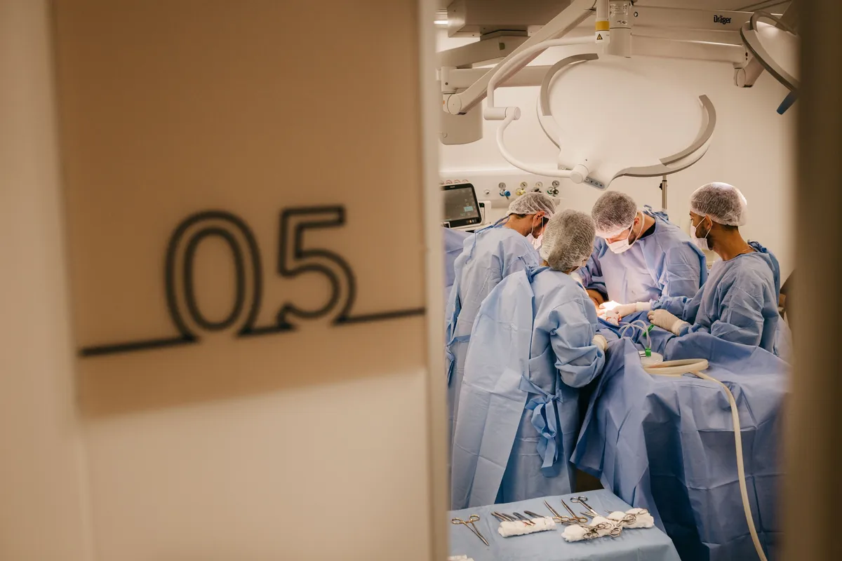 A surgical team in gowns and masks operating on a patient in a sterile operating room.